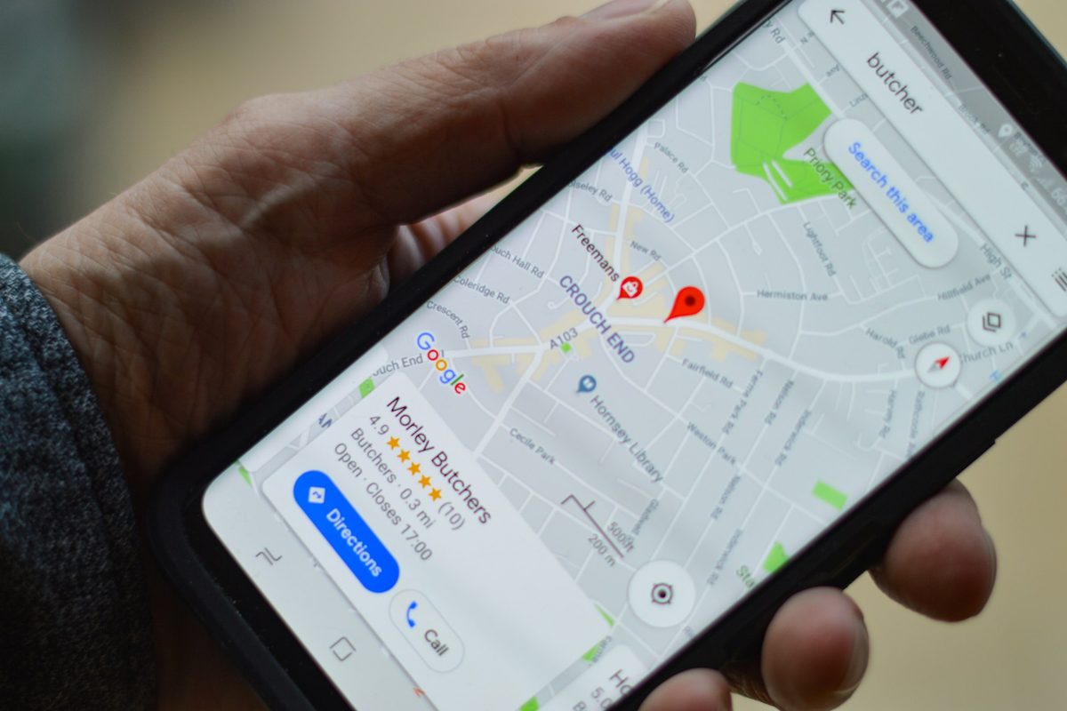 A hand holding a phone showing a local business listing on Google Maps