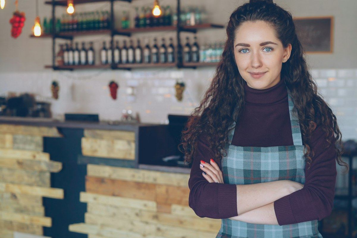 A smiling café owner standing in front of her counter