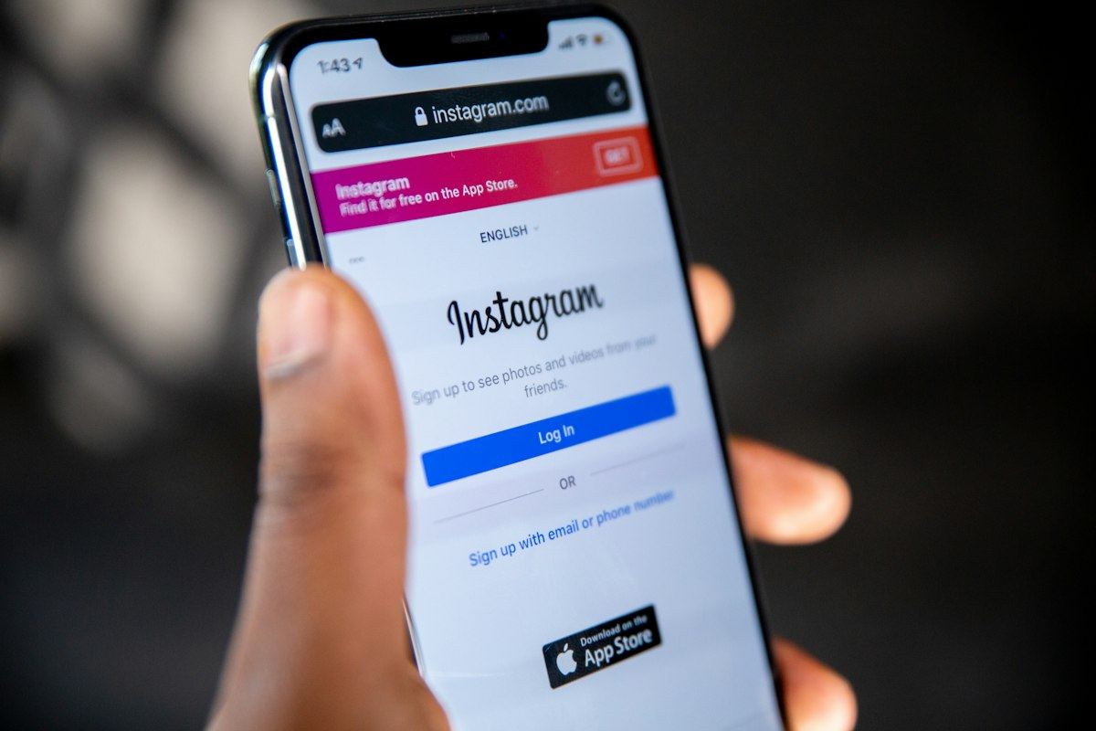 A hand holding a phone showing the Instagram login page