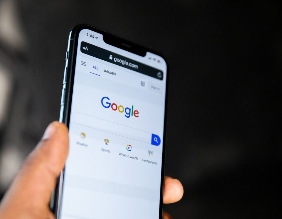 A hand holding a phone open on Google search