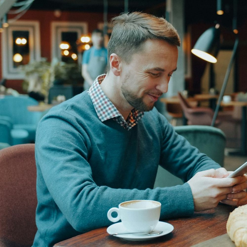 A man in a cafe looking something up on his phone