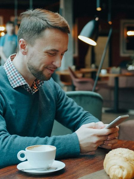 A man in a cafe looking something up on his phone