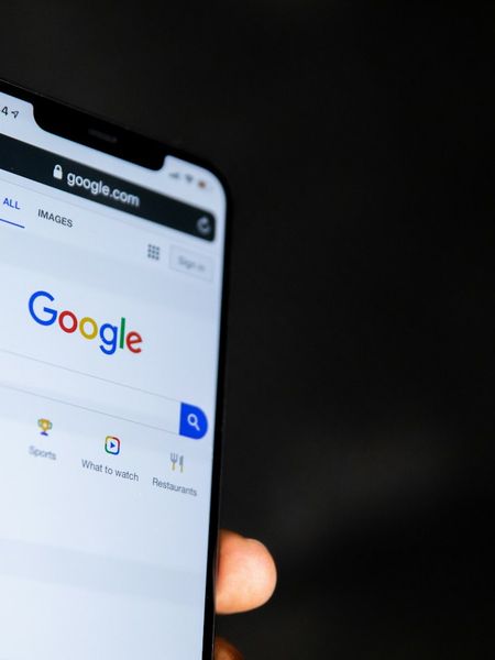A hand holding a phone open on Google search