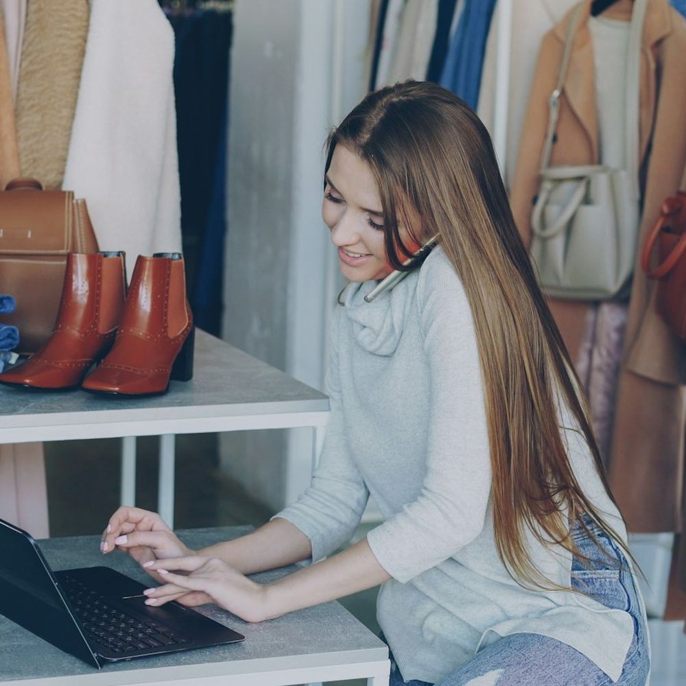 A shop owner updating her website on a laptop among her stock